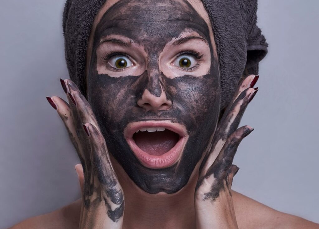 Überraschte Frau mit Gesichtspflege-Maske Cremes– Sinnbild für Hautpflege-Überforderung und fehlende Klarheit